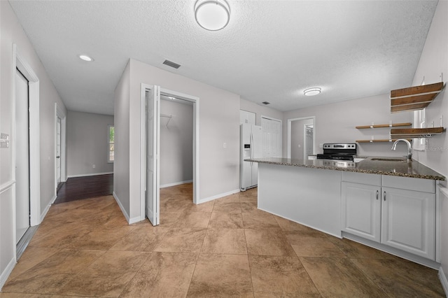 kitchen with sink, white cabinetry, electric range, white refrigerator with ice dispenser, and kitchen peninsula