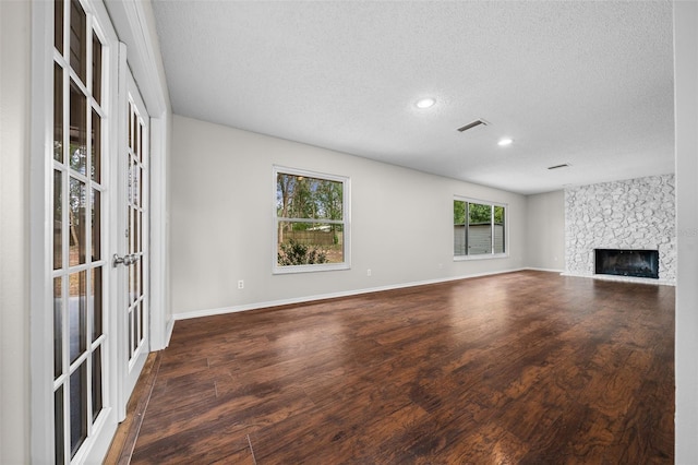 unfurnished living room with dark wood-type flooring, a fireplace, and a textured ceiling