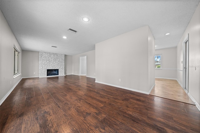 unfurnished living room featuring hardwood / wood-style flooring, a fireplace, and a textured ceiling