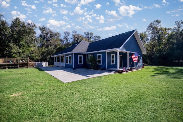 rear view of house with a deck, a patio area, and a lawn