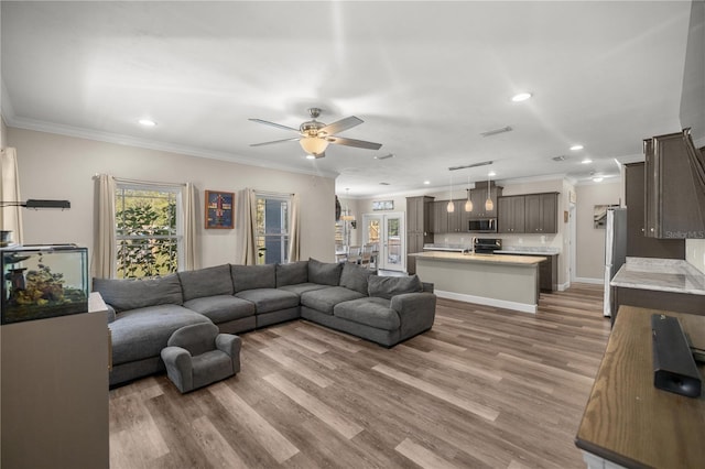 living room with ornamental molding, ceiling fan, and light hardwood / wood-style floors