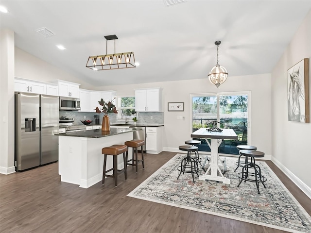 dining room with lofted ceiling, dark hardwood / wood-style flooring, a notable chandelier, and plenty of natural light