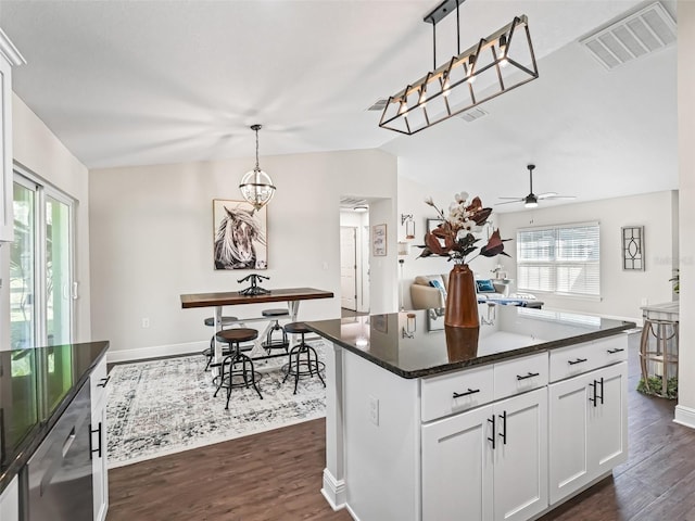 kitchen featuring dark hardwood / wood-style flooring, decorative light fixtures, white cabinets, and a kitchen island