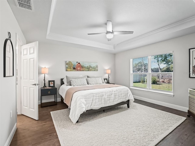 bedroom featuring ceiling fan, a tray ceiling, and dark hardwood / wood-style flooring