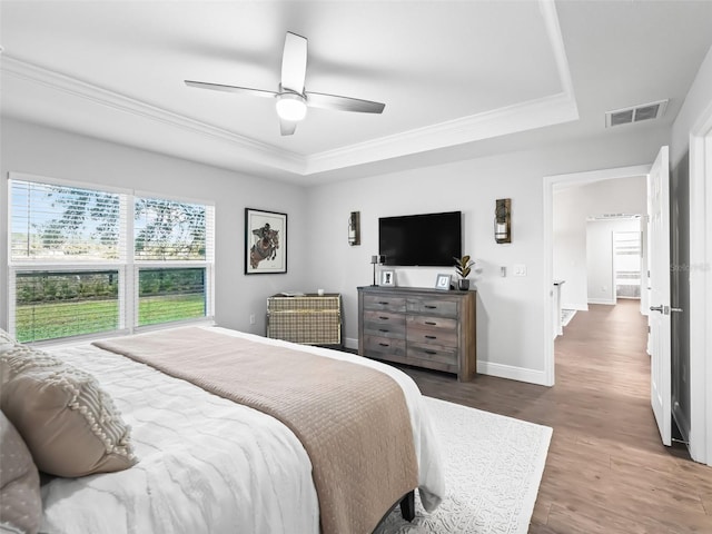 bedroom featuring crown molding, ceiling fan, a tray ceiling, and dark hardwood / wood-style flooring