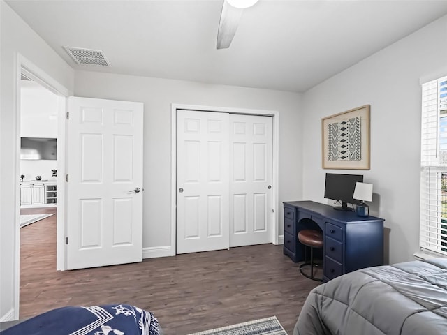 bedroom with dark wood-type flooring, ceiling fan, and a closet