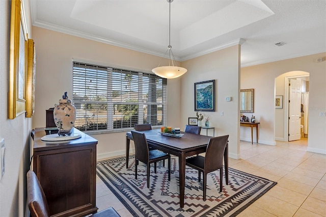 tiled dining space featuring ornamental molding and a raised ceiling