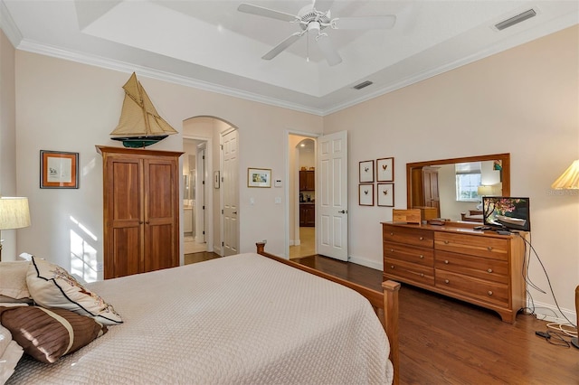 bedroom with a tray ceiling, dark wood-type flooring, and ornamental molding