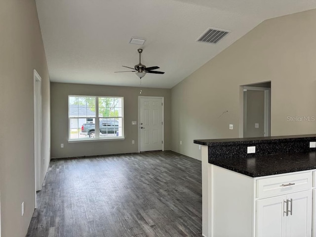 kitchen featuring ceiling fan, dark wood-type flooring, dark countertops, lofted ceiling, and open floor plan