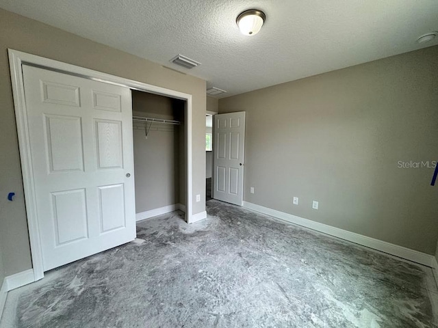 unfurnished bedroom featuring a closet, a textured ceiling, and baseboards