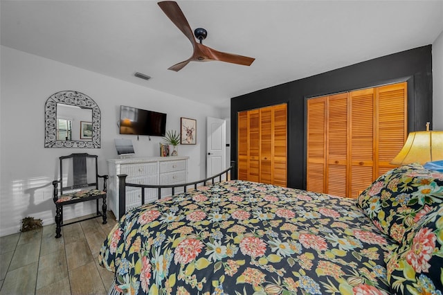 bedroom featuring multiple closets, light wood-type flooring, and ceiling fan