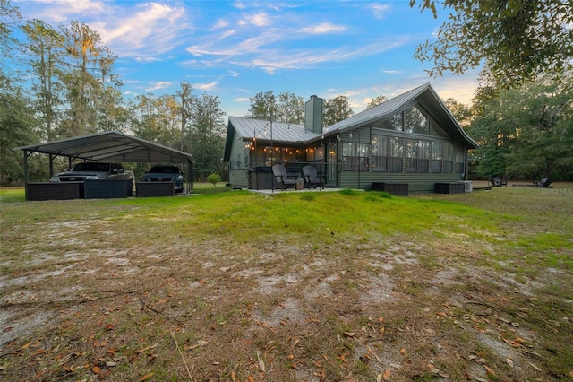 back house at dusk with cooling unit, a yard, a sunroom, and a carport