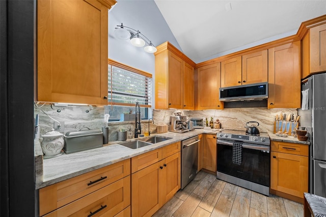 kitchen featuring stainless steel appliances, sink, backsplash, and light stone counters
