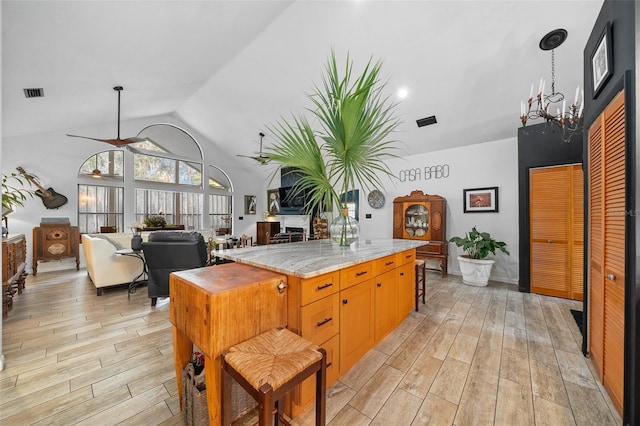 kitchen featuring hanging light fixtures, a kitchen island, ceiling fan, and light hardwood / wood-style floors