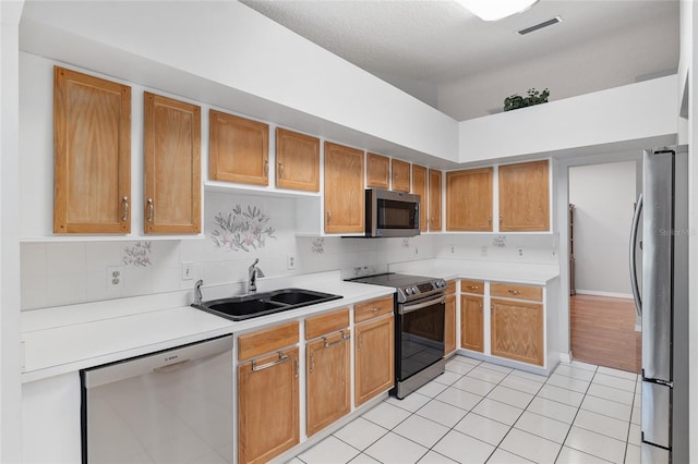 kitchen with light tile patterned floors, appliances with stainless steel finishes, light countertops, a sink, and visible vents