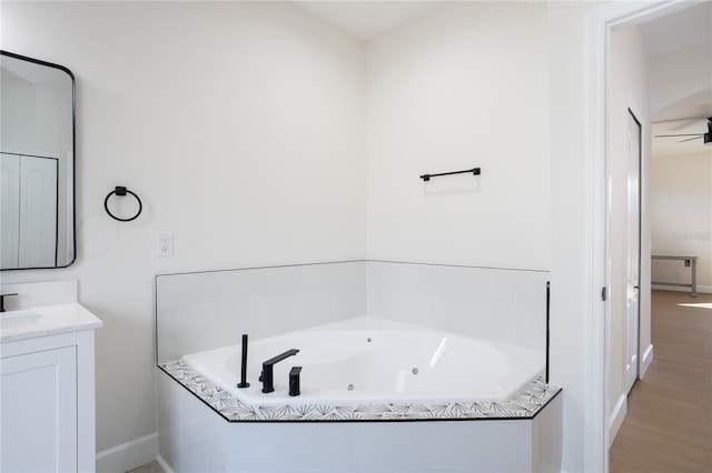 full bathroom featuring baseboards, a jetted tub, wood finished floors, and vanity