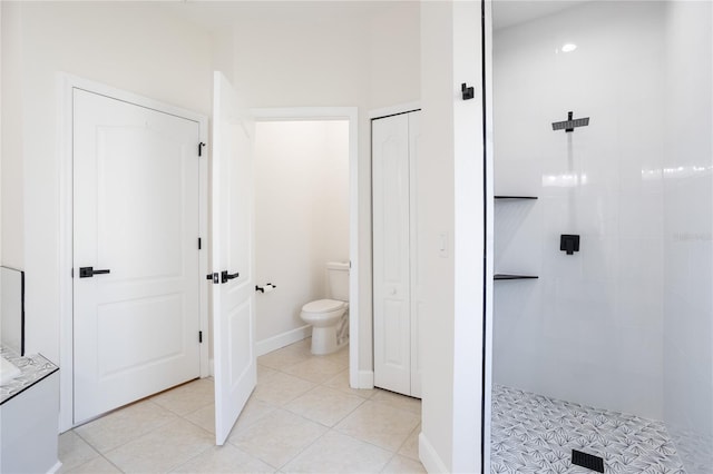 full bathroom with tile patterned flooring, toilet, tiled shower, and vanity