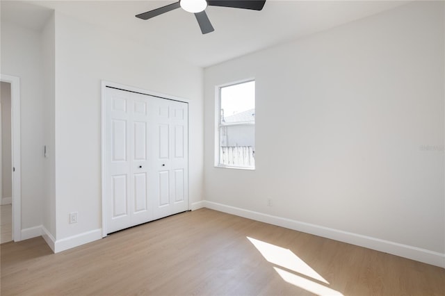 unfurnished bedroom featuring a closet, ceiling fan, baseboards, and light wood-style floors