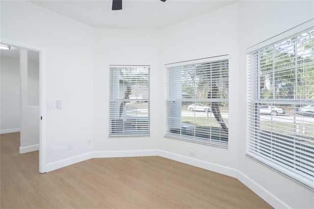 unfurnished room with a ceiling fan, light wood-type flooring, and baseboards