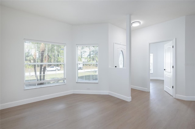 spare room featuring baseboards and wood finished floors