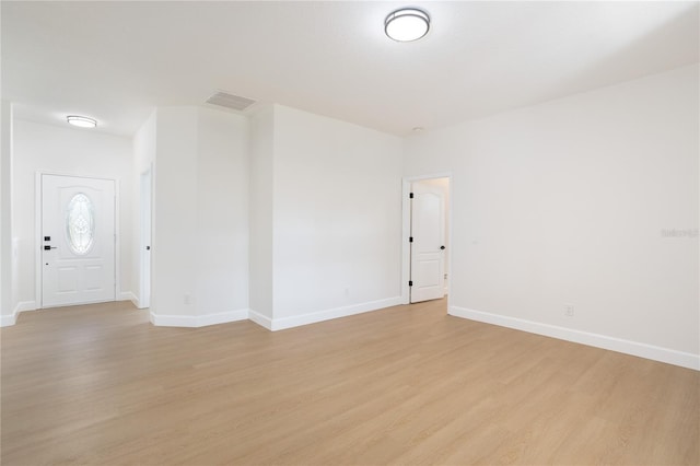 spare room featuring light wood finished floors, visible vents, and baseboards