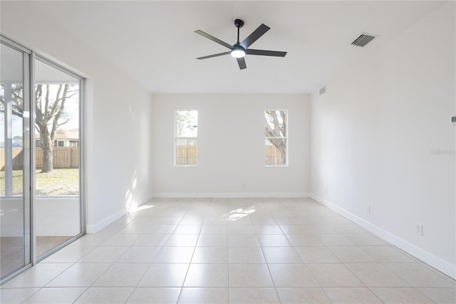 empty room featuring a wealth of natural light, visible vents, a ceiling fan, and light tile patterned floors