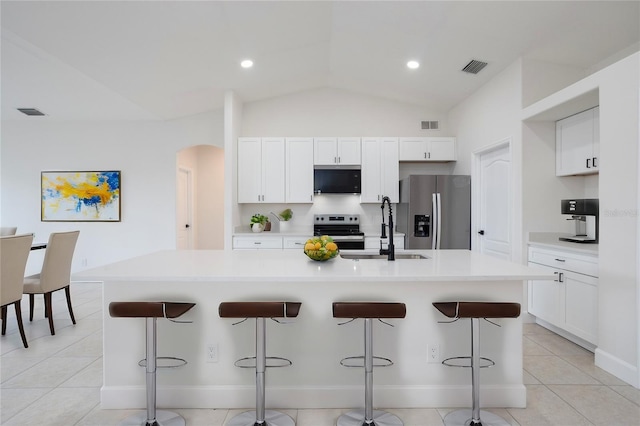 kitchen with visible vents, a kitchen island with sink, a sink, arched walkways, and appliances with stainless steel finishes