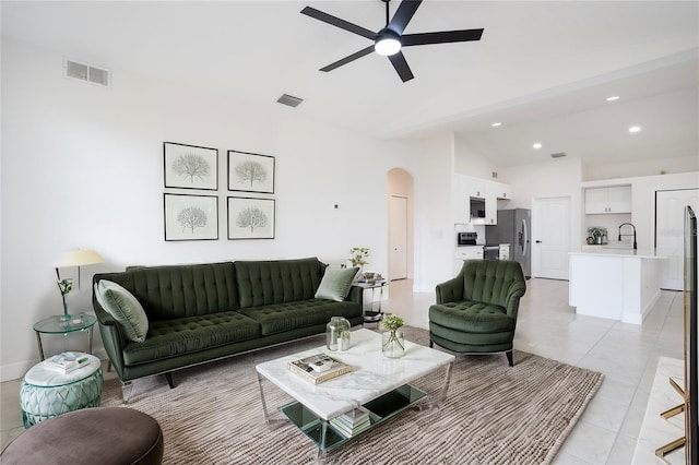 living area with arched walkways, visible vents, light tile patterned floors, and vaulted ceiling