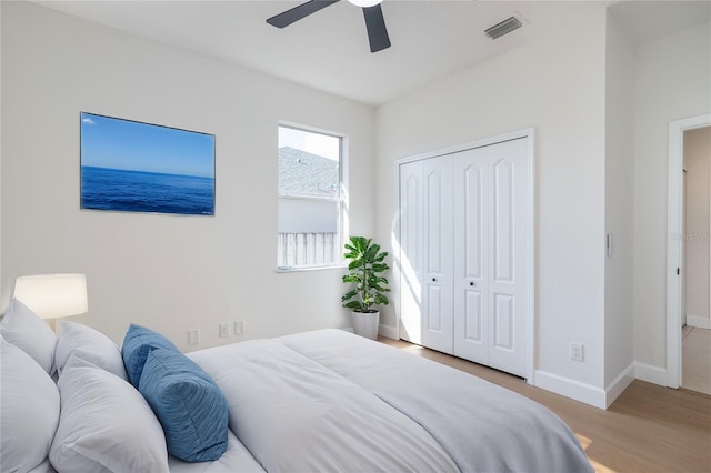 bedroom featuring visible vents, ceiling fan, baseboards, wood finished floors, and a closet