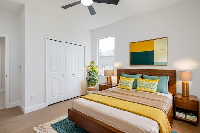 bedroom with light wood-type flooring, baseboards, a closet, and a ceiling fan