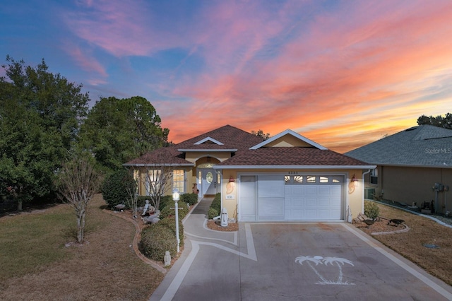 ranch-style house with a garage, roof with shingles, driveway, and stucco siding