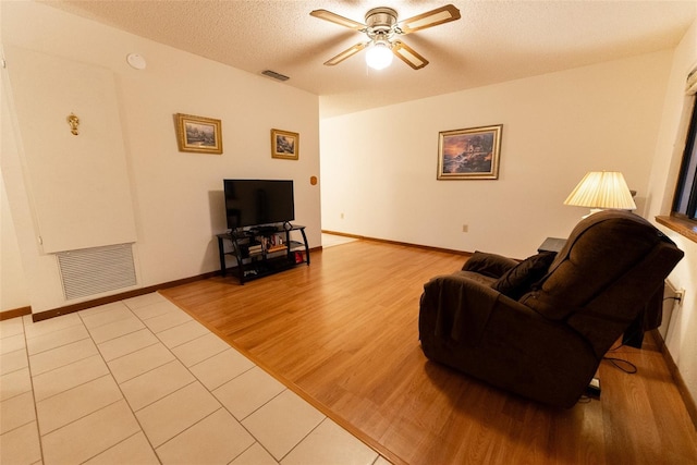 living room with ceiling fan, light hardwood / wood-style floors, and a textured ceiling