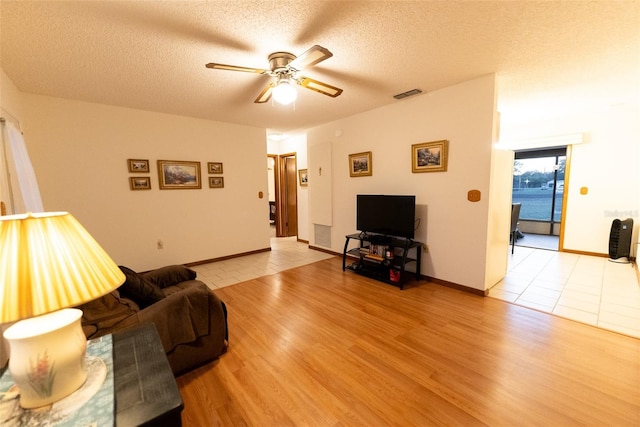 living room with ceiling fan, light hardwood / wood-style flooring, and a textured ceiling