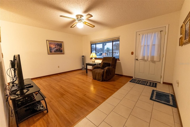 entrance foyer with ceiling fan, a textured ceiling, and light wood-type flooring