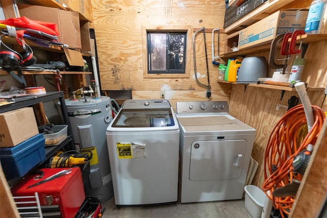 laundry room with water heater, washer and dryer, and wood walls