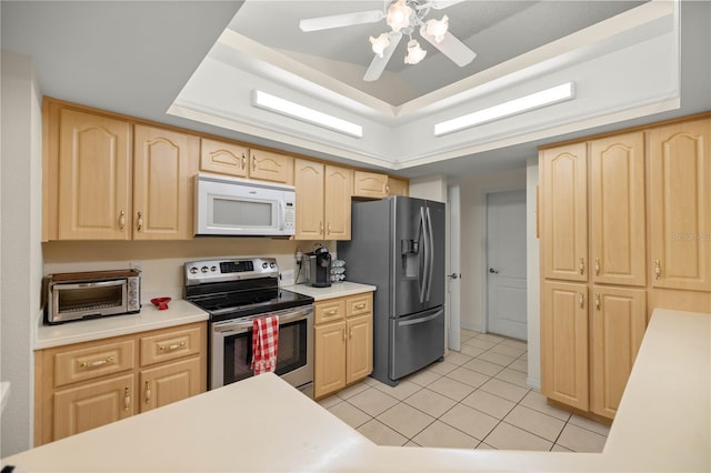 kitchen featuring a raised ceiling, a toaster, light brown cabinets, and appliances with stainless steel finishes