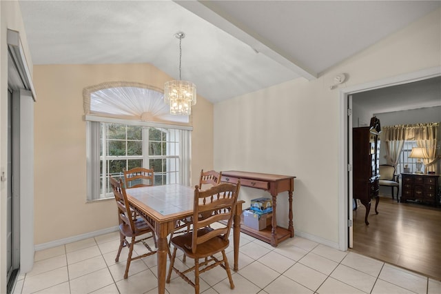 dining area with lofted ceiling, light tile patterned floors, baseboards, and a chandelier