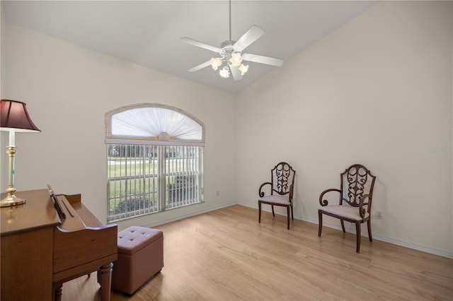 sitting room with light wood finished floors, baseboards, ceiling fan, and vaulted ceiling