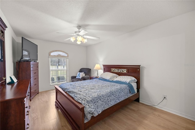 bedroom with baseboards, light wood-style floors, ceiling fan, and a textured ceiling