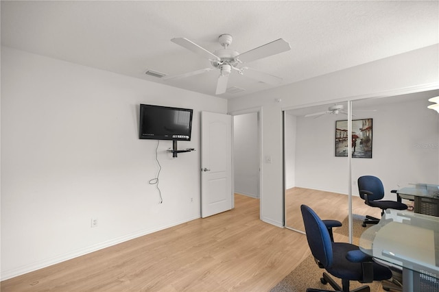 office featuring ceiling fan, visible vents, baseboards, and light wood-style flooring