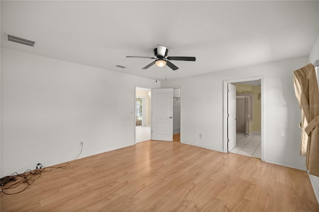 unfurnished bedroom with visible vents, baseboards, light wood-style flooring, and a spacious closet