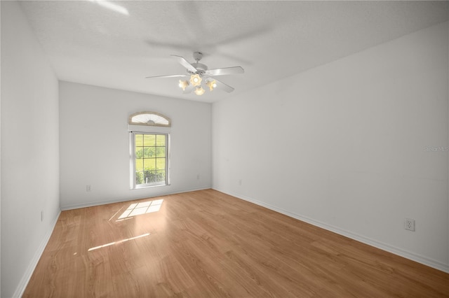 spare room with baseboards, wood finished floors, and a ceiling fan