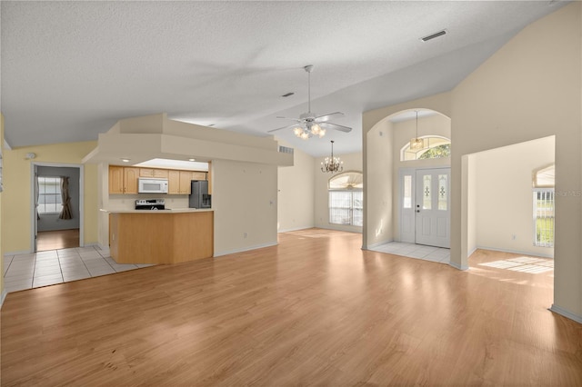 unfurnished living room with lofted ceiling, visible vents, and a healthy amount of sunlight