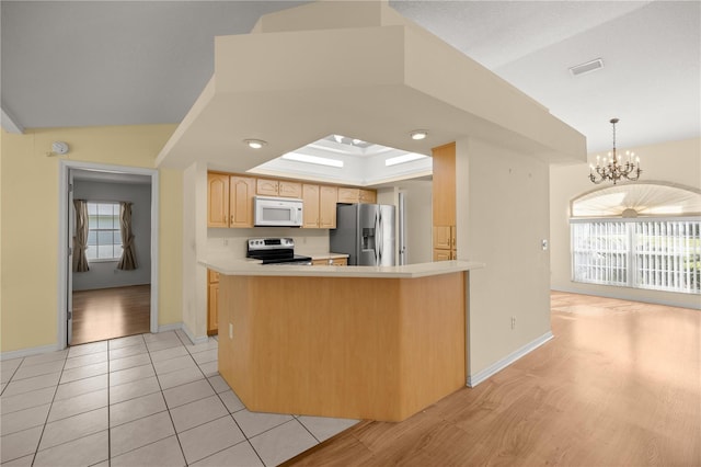 kitchen with a healthy amount of sunlight, light brown cabinetry, a chandelier, appliances with stainless steel finishes, and visible vents