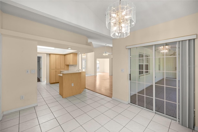 kitchen featuring a peninsula, light brown cabinetry, light countertops, ceiling fan with notable chandelier, and open floor plan