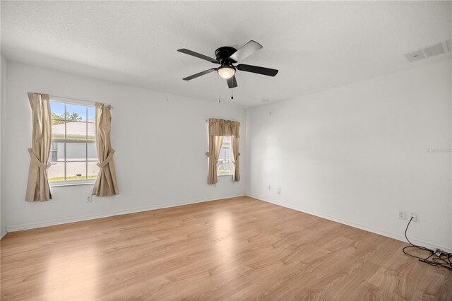 unfurnished room featuring light wood finished floors, visible vents, ceiling fan, and baseboards