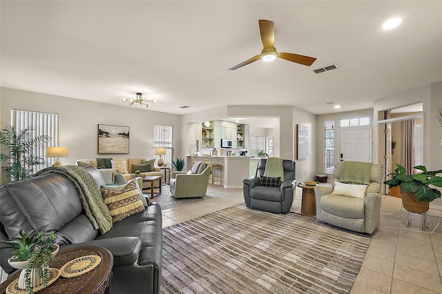 living area featuring light tile patterned floors, visible vents, a wealth of natural light, and ceiling fan