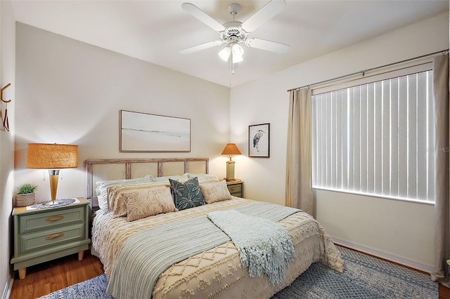 bedroom with a ceiling fan, wood finished floors, and baseboards