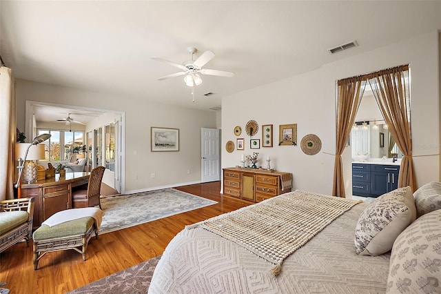 bedroom featuring visible vents, ensuite bathroom, a ceiling fan, wood finished floors, and baseboards