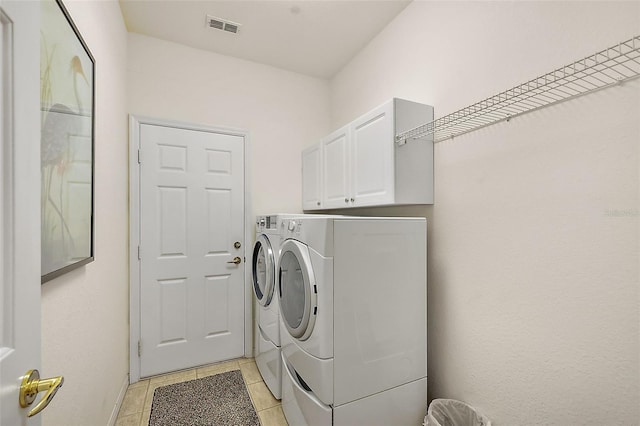 washroom with light tile patterned floors, cabinets, and washer and dryer